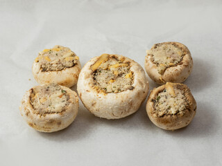 Breadcrumbs, herb and cheese stuffed mushrooms cup on grey color cooking paper. High quality product.
