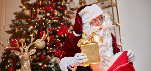 Santa Claus with red bag full of gifts for children at home. New year and Merry Christmas concept