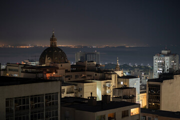 Fototapeta na wymiar Night view of the city center of Porto Alegre, highlighting the dome of the Metropolitan Cathedral, with Lake Guaíba in the background and, beyond it, lights from another city in the distance