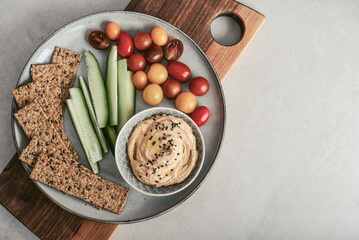 Bowl with hummus, cucumber, cherry tomatoes and crispbread