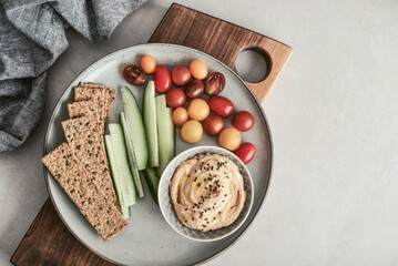 Bowl with hummus, cucumber, cherry tomatoes and crispbread