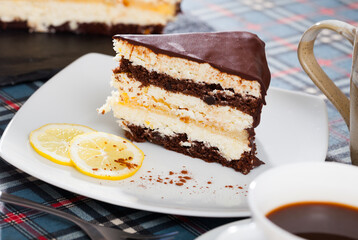 Slice of delicious chocolate lemon cake served on white plate with sliced lemon ..