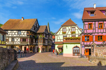 A small cobblestone square near the Castle Bridge with colorful half timber buildings with shops and cafes in the Alsatian village of Kaysersberg, France.