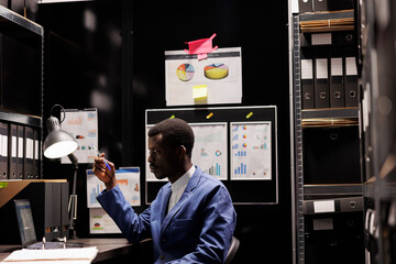 African american police officer analyzing criminology report, checking crime scene files on laptop...