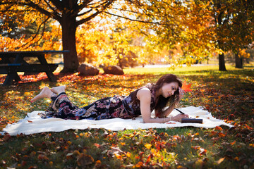 Woman lying down outdoor in fall and writing her journal 