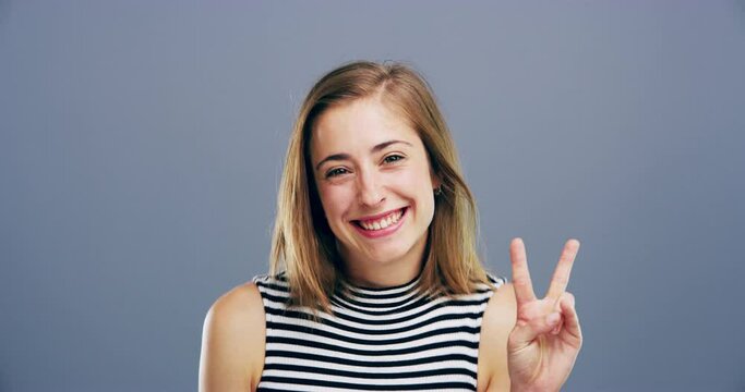 Face, smile and woman with peace sign in studio isolated on a gray background mockup space. Portrait, happy person and v hand gesture for victory, winner symbol and emoji for achievement of success