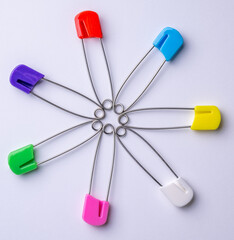 Seven colourful diaper safety pins in a circle