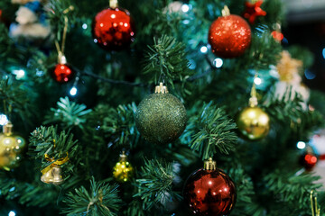 Obraz na płótnie Canvas Bright sparkling glass balls hang on the green branches of the Christmas tree