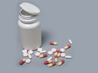 Pills spilling out of pill bottle white and two-colored capsules pills  Medicines and prescription pills flat lay background. White medical pills and tablets spilling out of a drug bottle.