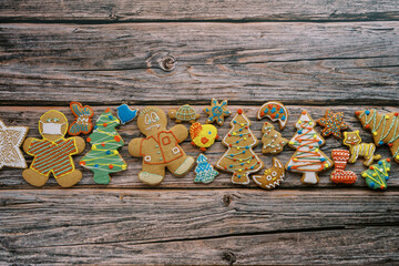 Glazed Christmas cookies lie in a row in the center on a rough dark wooden background