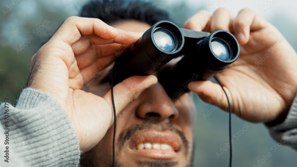 Poster Face, hiking and man with binocular in nature for sightseeing, explore or trekking a mountain environment. Travel, adventure and view with a young male hiker closeup outdoor in the woods or forest