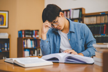 Students feel tired and stressed after working on their laptops and looking for books to study, make reports, find useful information in the university room.