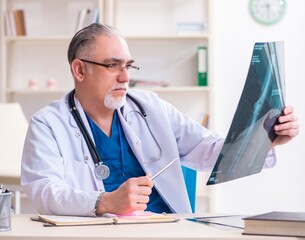 Old male doctor working in the clinic