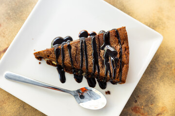 Piece of delicious brawny with walnuts served in a ceramic plate with teaspoon on the table