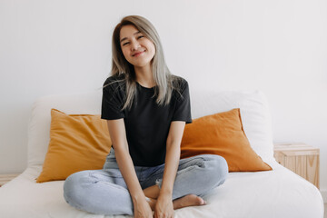 Happy asian woman sits and relax on sofa in one good fine day.