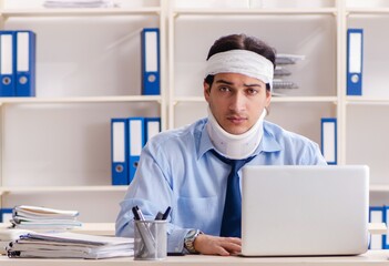 Young injured male employee working in the office