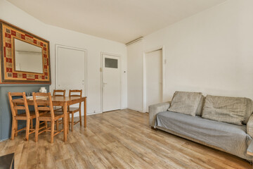 a living room with a couch, table and mirror on the wall next to the sofa is a wooden floor