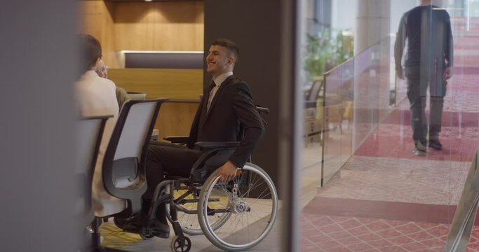 A director in a wheelchair demonstrates the values of inclusivity and leadership by attending a meeting in the office, highlighting the importance of equal opportunities in the corporate world.