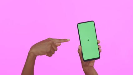 Hands, pointing at green screen and smartphone, advertising mockup with app and ads on pink background. Tracking marker, person in studio with online information for website and tech marketing