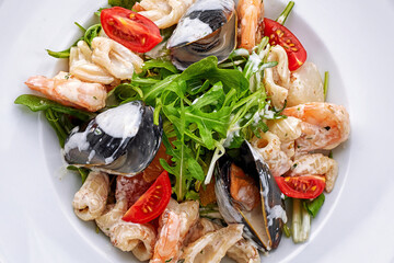 Seafood salad with mussels, squid, shrimp, on a round white
