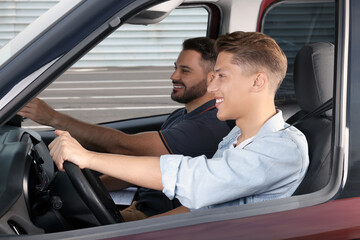 Driving school. Happy student during lesson with driving instructor in car