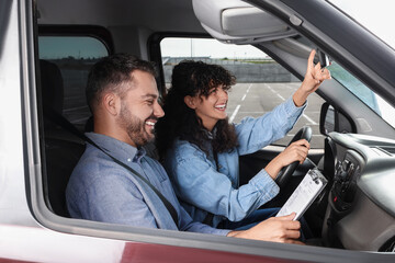 Obraz premium Driving school. Happy student passing driving test with examiner in car at parking lot