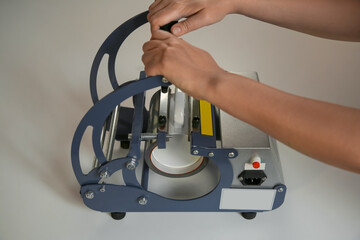 Printing logo. Woman with mug using heat press at white table, closeup