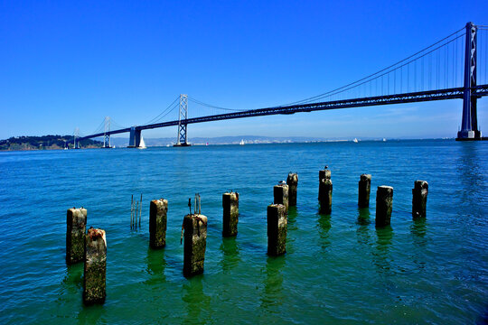 Remnant cement piles and rebar from Old San Francisco pier with the San Francisco Oakland Bay Bridge in background 