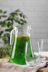 Jug of homemade refreshing tarragon drink and glasses on table
