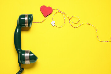 Long-distance relationship concept. Telephone receiver, decorative cord and paper heart on yellow background, flat lay with space for text