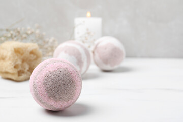 Bath bombs, loofah sponge and candle on white table, space for text