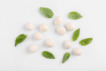 Tasty mozzarella balls and basil leaves on white background, flat lay