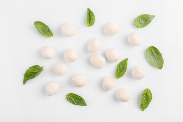 Tasty mozzarella balls and basil leaves on white background, flat lay