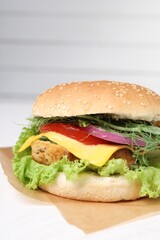 Delicious burger with tofu and fresh vegetables on white table, closeup