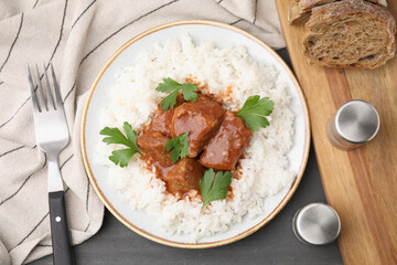 Delicious goulash served with rice on grey wooden table, flat lay