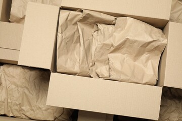 Many open cardboard boxes with crumpled paper as background, top view