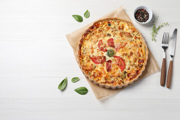 Tasty cheese quiche and cutlery on white wooden table, flat lay