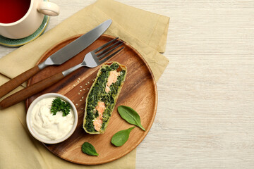 Delicious strudel with salmon and spinach served on light wooden table, flat lay. Space for text