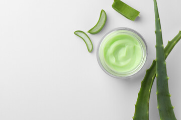 Jar of natural cream and cut aloe leaves on white background, flat lay. Space for text