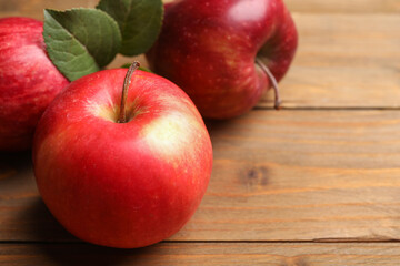 Fresh red apples on wooden table, closeup. Space for text