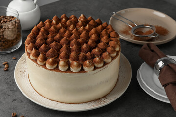Delicious tiramisu cake with cocoa powder on grey table