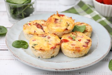 Delicious egg muffins with cheese and bacon on white wooden table, closeup
