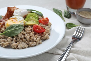 Delicious boiled oatmeal with poached egg, bacon, avocado and tomato served on table, closeup