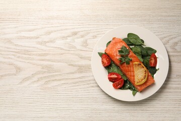 Tasty grilled salmon with tomatoes, lemon and basil on white wooden table, top view. Space for text