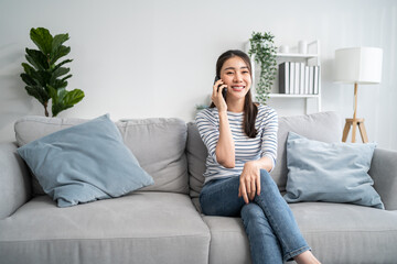 Asian beautiful woman sit on sofa and talk on mobile phone in house. 