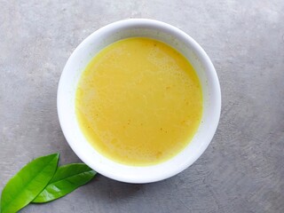 Homemade chicken stock in a bowl on a gray background. soup. chicken gravy. yellow sauce. ingredients. delicious.
