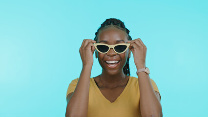 Face, happiness and black woman with glasses, silly or cheerful girl on a blue studio background. Portrait, African person or model with funky eyewear, trendy or goofy with casual outfit or happiness