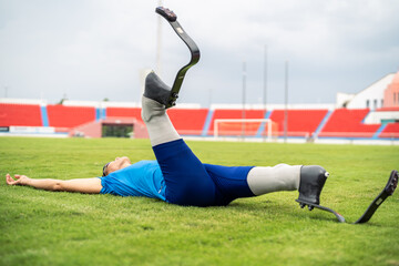 Asian para-athlete with prosthetic blades stretching leg in stadium.