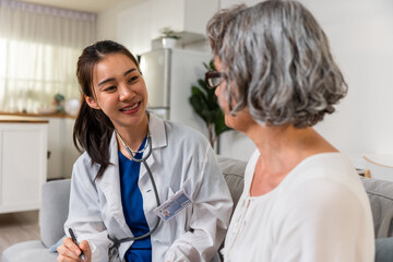 Asian caregiver nurse examine Caucasian senior woman patient at home. 