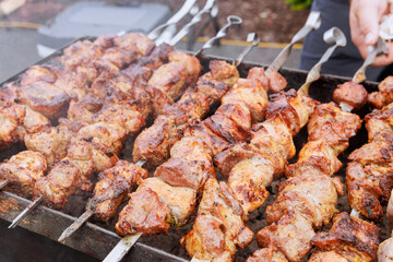 Traditionally cooked Turkish kebabs on skewers at hot grill, prepared outdoors in open air